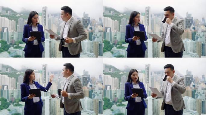 商业伙伴在窗边讨论工作，背景是香港岛的建筑景观。