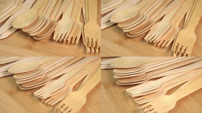 木制环保一次性餐具旋转。一排木勺、刀叉放在砧板上。厨房、餐厅一次性生态餐具