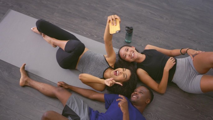 自拍，瑜伽和一群朋友在健身房健身，健康的身体和社交媒体在工作室的帖子。健身，和平标志和男女拍照在手机