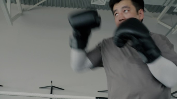 亚洲职业拳击手独自训练的肖像，阴影集中在健身房的锻炼