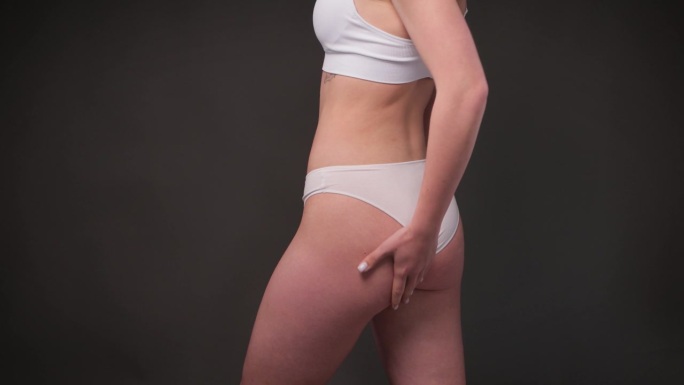 女孩拉腹部和臀部的皮肤，显示身体脂肪。处理和处置多余的体重，皮下脂肪的沉积。