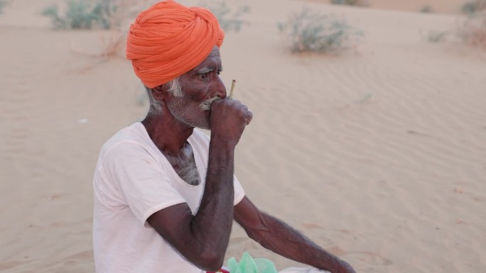一名印度男子正在准备印度奶茶，一边抽着烟