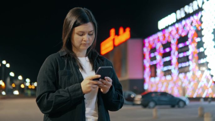 女孩手里拿着手机，背景是散景灯