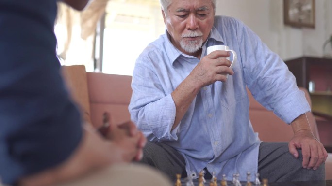 亚洲老人和儿子在家里下棋