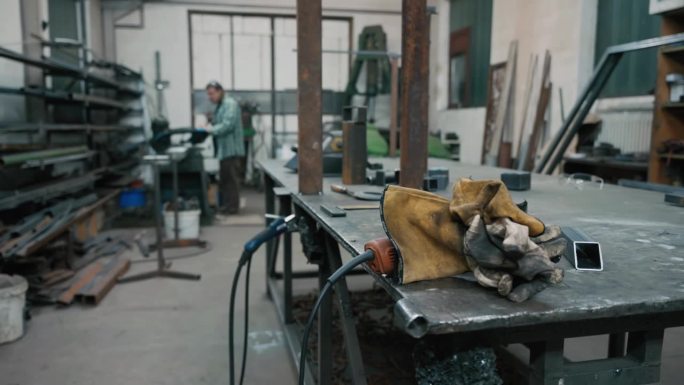 金属工业工作台上脏手套和焊枪的SLO - MO特写