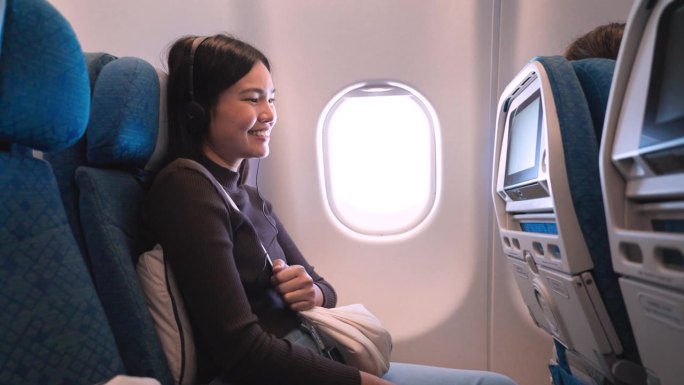 机上娱乐:她在一架商用飞机的经济舱座位上轻敲屏幕。