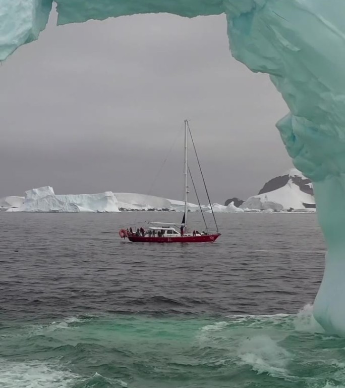 南极巨大的白色冰山拱中轮船的垂直视频视图。