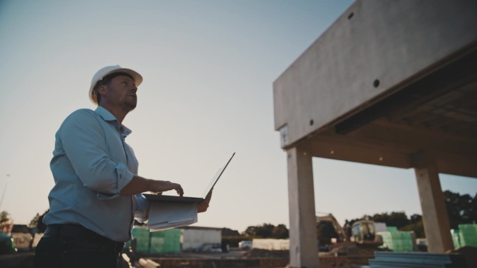 男建筑工人用手提电脑检查在建的建筑