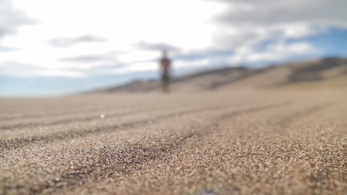 沙漠中吹沙与走向相机的模糊人物特写