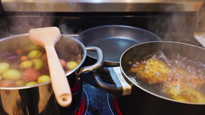 煮肉汤和土豆煮在热气腾腾的锅用木铲在炉子上
