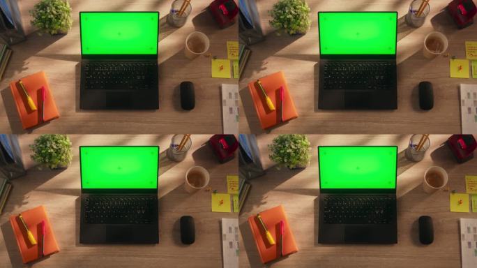 从上往下看一台笔记本电脑，配有模拟绿屏Chromakey显示屏和运动追踪器，它站在一张木制办公桌上，