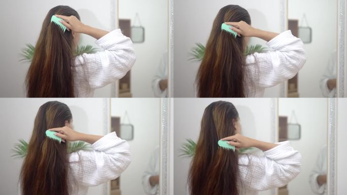 女人轻轻地梳理她长长的健康的头发，在家里练习细致的头发护理。