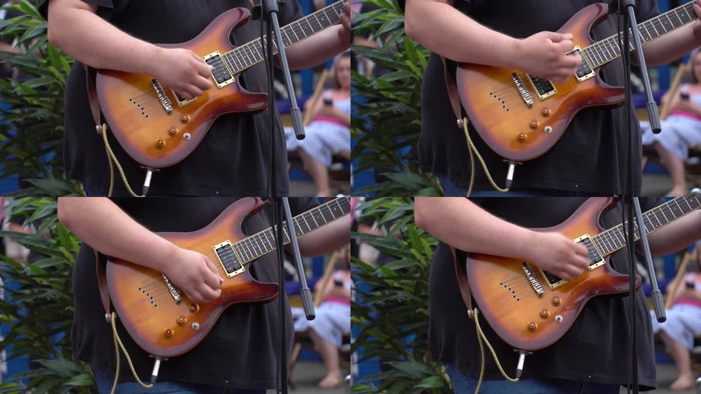 吉他手在街头音乐节上用电吉他演奏吉他即兴片段。露天演出的翻唱乐队