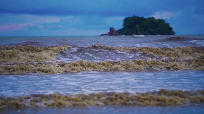 大海里的大浪打在沙滩上，海水浑浊。