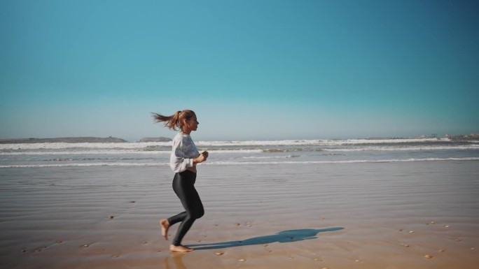 一个女人沿着海岸线在沙滩上慢跑