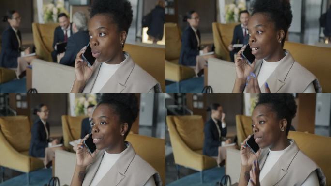 美丽的非洲裔美国女士在现代酒店大堂的室内用手机谈论旅行
