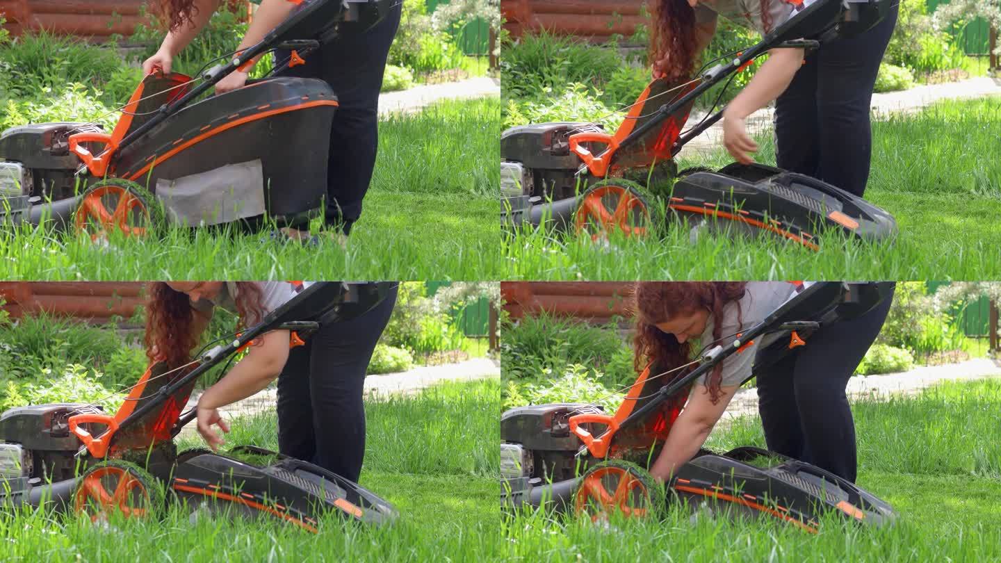 夏日，一名女子打开割草机容器，用手在乡间别墅附近后院的绿色草坪上铺草。女房东正在打扫房间。家庭花园的