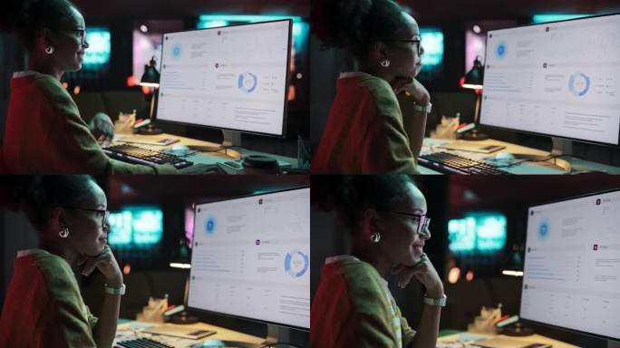 一个快乐成功的黑人女商人的肖像在创意机构使用台式电脑在晚上。非裔美国女性在检查数据和统计图表时微笑