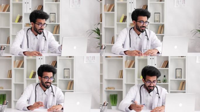 穿着白大褂的聪明友好的印度男性临床医生在医院办公室用笔记本电脑远程咨询病人。远程医疗。网上预约医生。