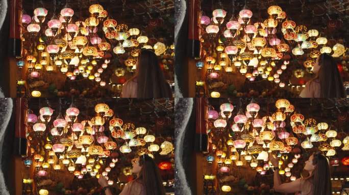 一名年轻女子走进一家土耳其纪念品商店，天花板上挂着彩色玻璃制成的吊灯。