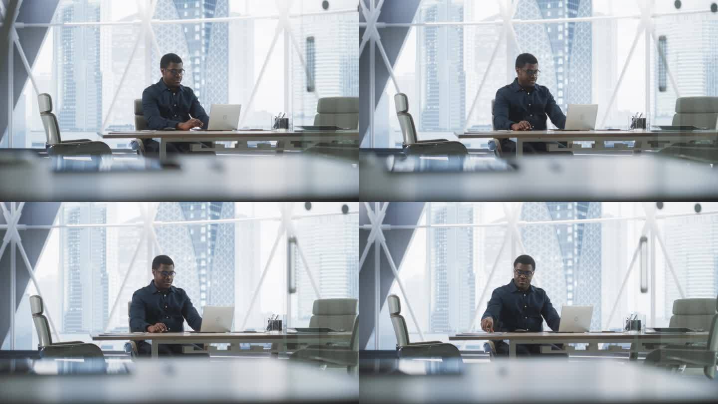 成功的黑人商人在他的大城市角落办公室里用笔记本电脑工作的肖像。非裔美国男性数字企业家为电子商务战略评