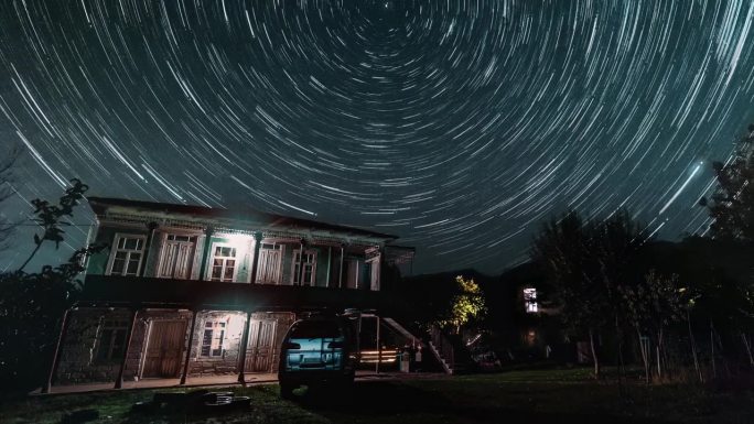 高加索乡村的老房子和繁星点点的天空，上面的光迹用超延时拍摄