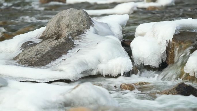冬天河水流淌，附近被冰雪覆盖的石头，镜头慢慢滑落到一边