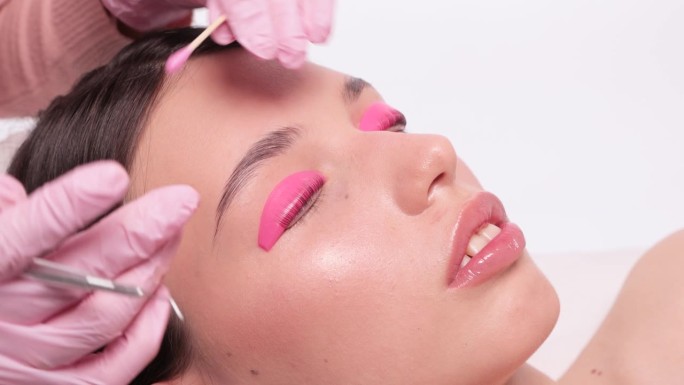 在美容院，化妆师正在为一位美女进行睫毛的分层和染色。睫毛扩展。睫毛特写