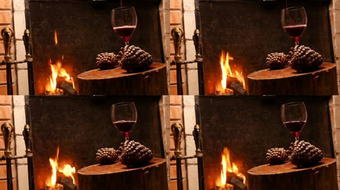 特写，侧面:端酒。把酒倒进杯子里。壁炉旁的一杯酒。木桌上的一杯红酒。壁炉旁的一杯酒。在壁炉里燃烧的木