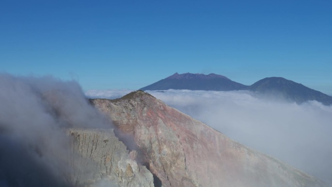 悬崖的云涌入火山的创造者在伊真山，东爪哇，印度尼西亚。蓝天复制空间。