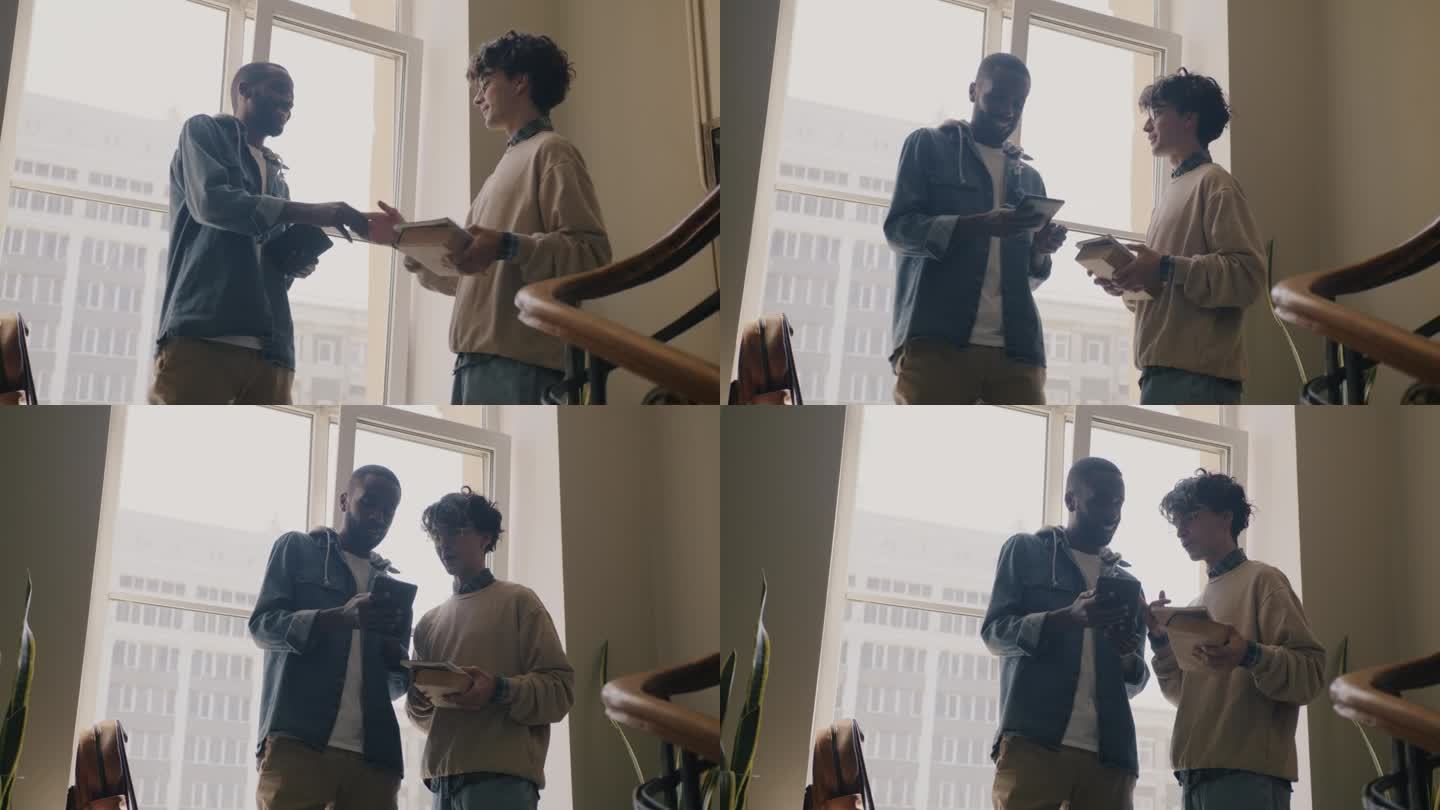 慢动作的年轻男子学生在大厅见面打招呼，用平板电脑交谈