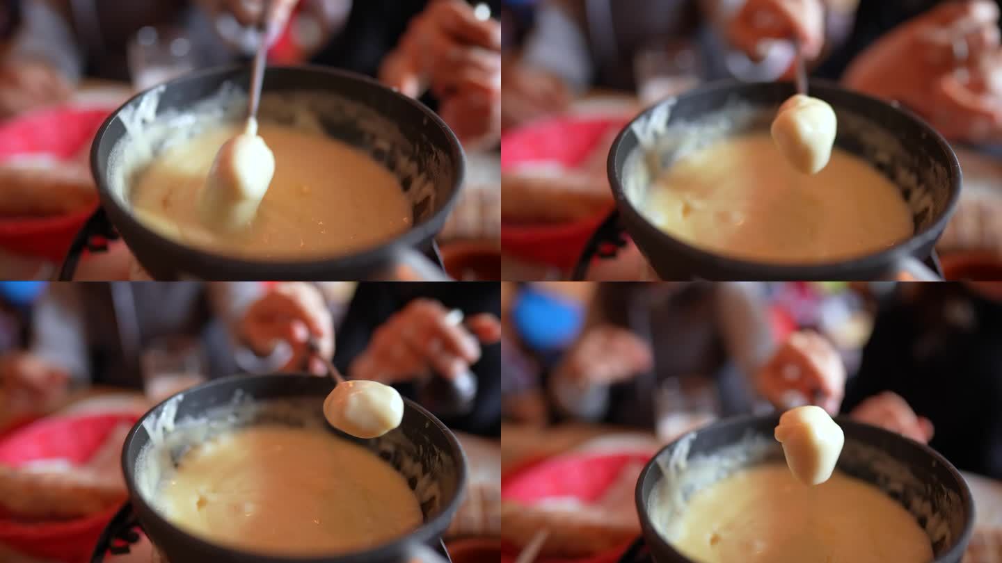奶酪火锅的特写镜头，用叉子盛着面包和奶酪——吃传统的瑞士美食