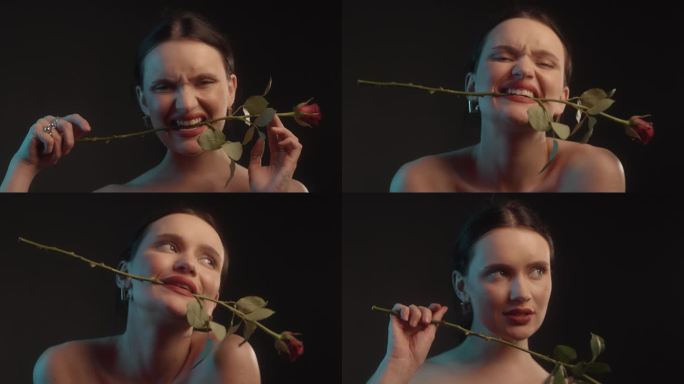 性感的女人用红色的口红和纹身黑色背景工作室拍摄跳舞与一个单一的红玫瑰，并把它在她的牙齿