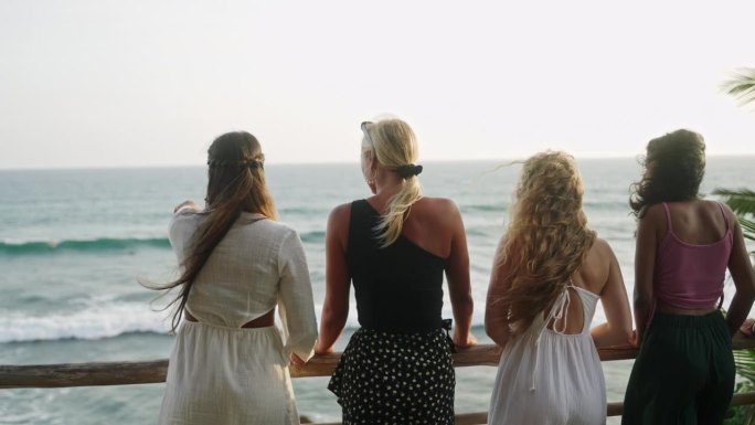 不同的女人看海。多民族的年轻女性在热带地区真正的露台上观看日落。高兴的多种族女孩欣赏黄昏的海景。后视