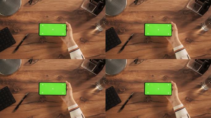 匿名人士使用智能手机模拟绿屏Chromakey显示与占位符。人竖着拿着手机，在木桌背景上看视频。自顶