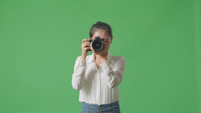 亚洲摄影师告诉模特在工作室里用绿幕背景拍照时左右移动