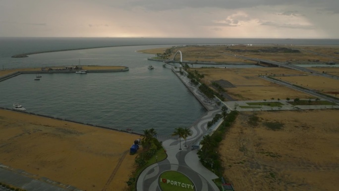 鸟瞰几乎空无一人的码头、海滨长廊和未来主义的人行桥。远处海上的阴雨天气。科伦坡，斯里兰卡