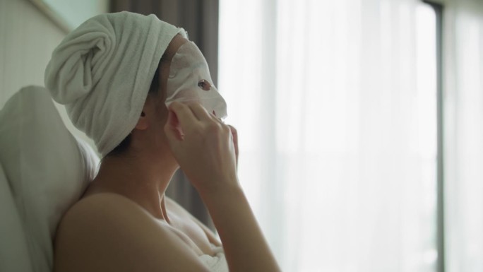 一名亚洲妇女正在做面膜，她的脸上有净化面膜