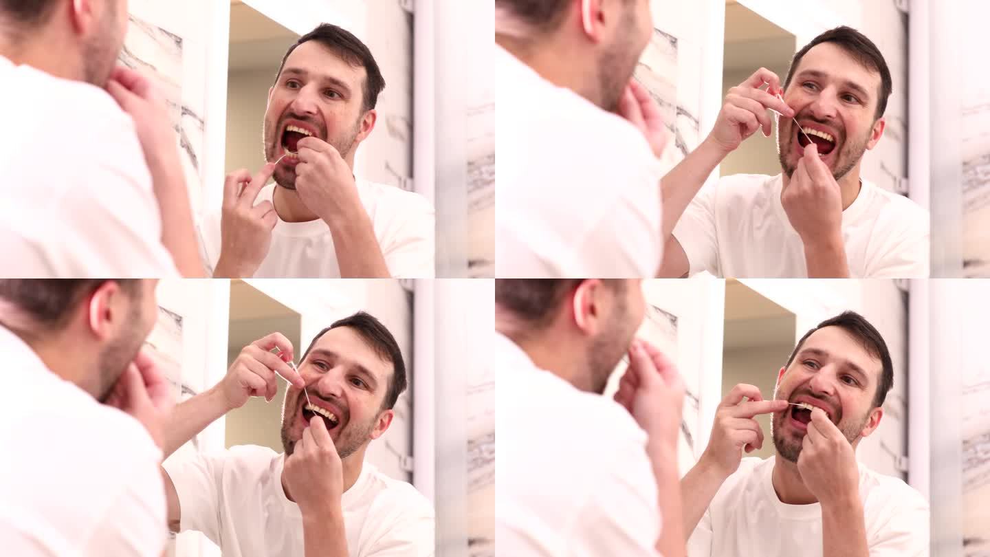 口腔卫生。一名男子用牙线清洁牙齿，看着家里浴室里的镜子。