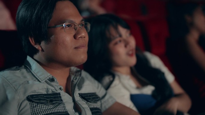 快乐的亚洲夫妇在电影院享受电影体验。