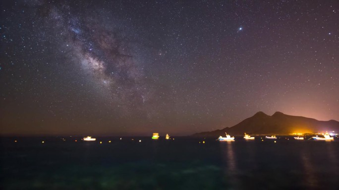 银河夜空中的海景，船和山