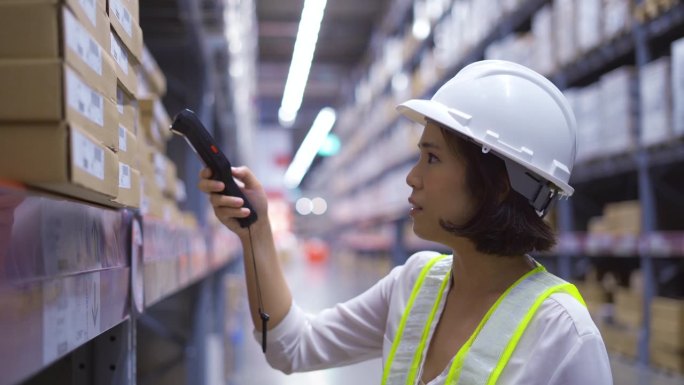 工人使用手持条码扫描器检查仓库大货架上的产品库存。