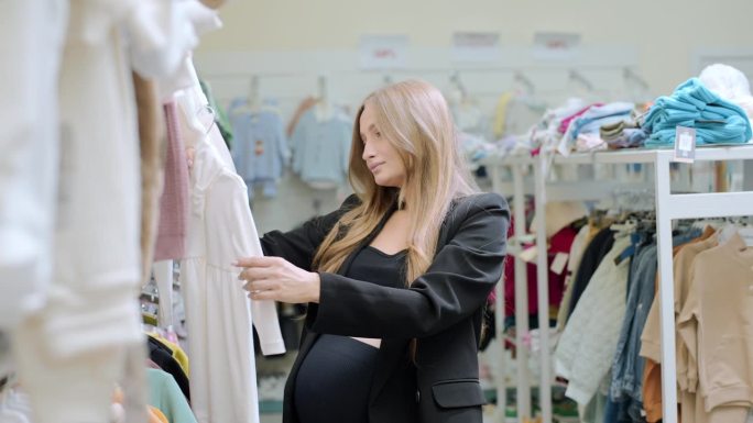 孕妇在童装店选购婴儿服装