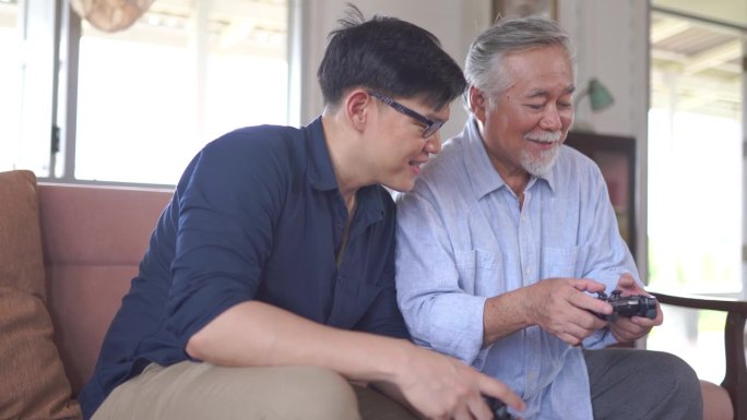 快乐的亚洲父子喜欢在家里的客厅里用操纵杆玩电子游戏