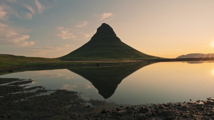 冰岛夏季，Kirkjufell山上的金色日出与湖水的倒影