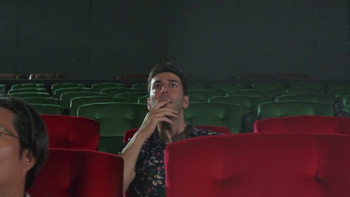 男性观众在影院观看戏剧电影时表达情感。