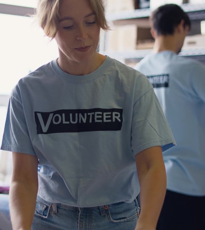 男性和女性慈善志愿者在食物银行整理捐款的垂直视频