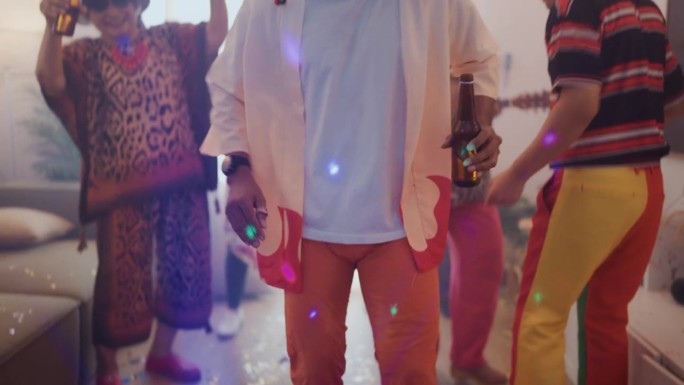 亚洲男人穿着五颜六色的衣服，拿着啤酒，和朋友们一起随着他们最喜欢的歌曲跳舞。在新年晚会上