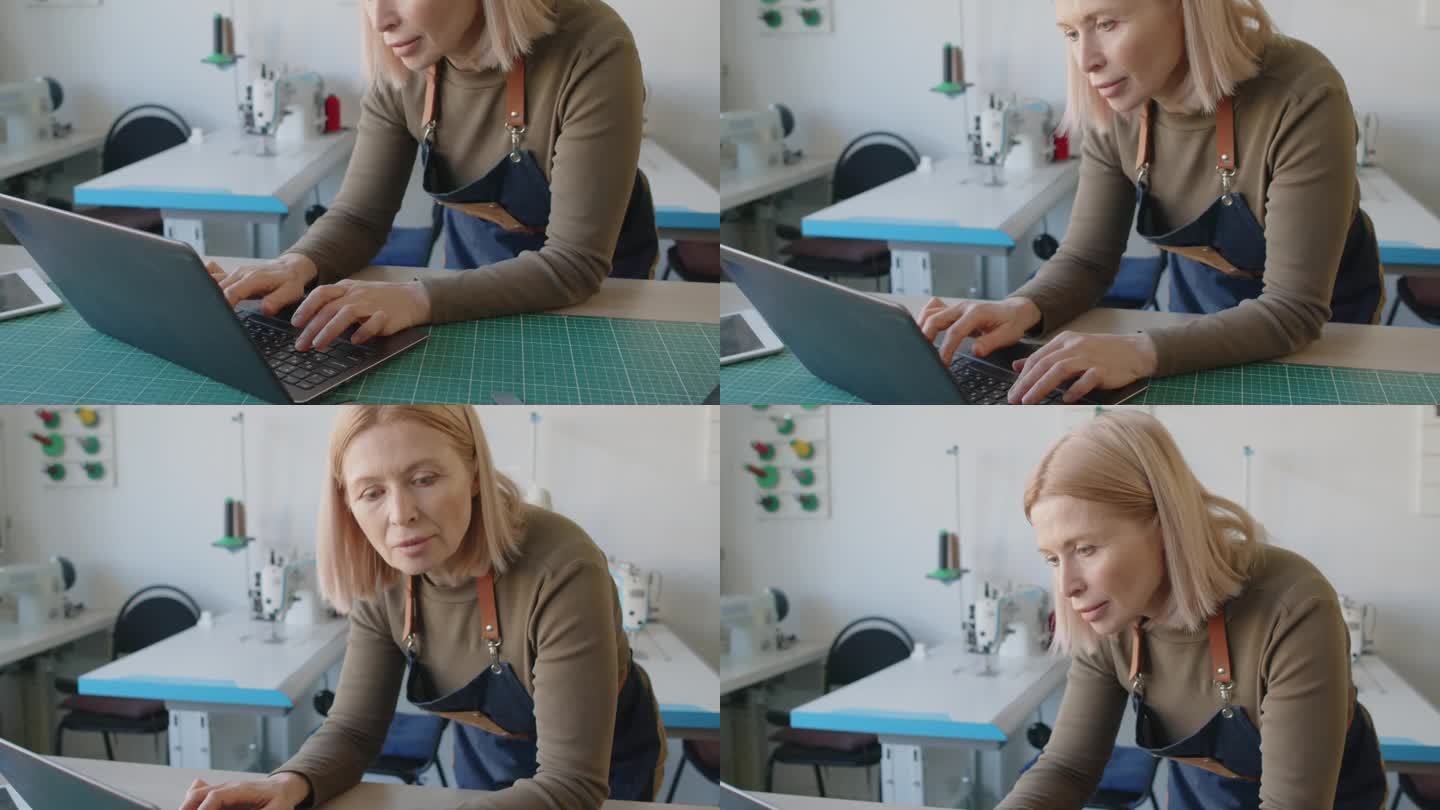 中年白人女裁缝在工作室用笔记本电脑打字