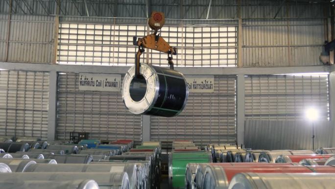 在生产厂的原料仓库上，机器正在将卷成卷的铝卷板一层层提起。
